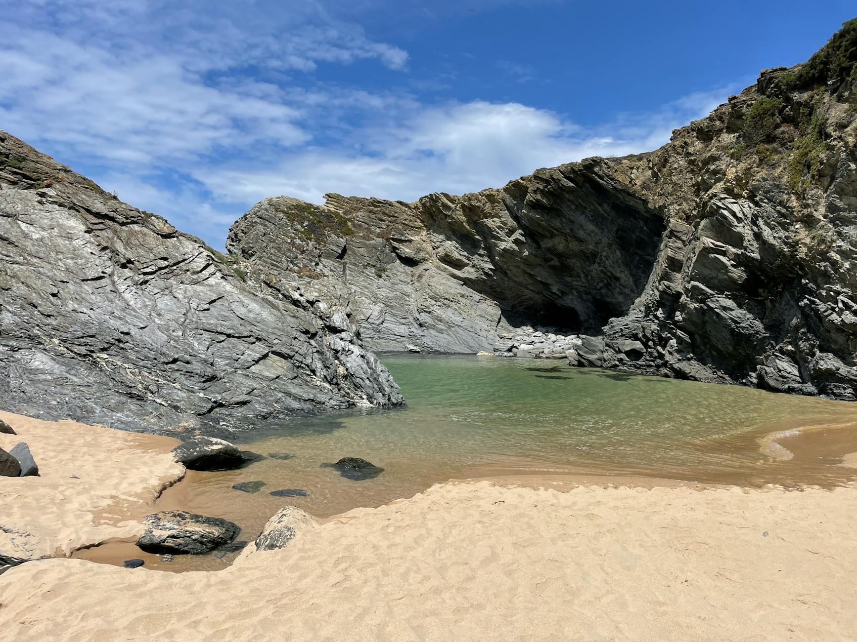 A secluded hidden cove beach in Cornwall surrounded by towering cliffs