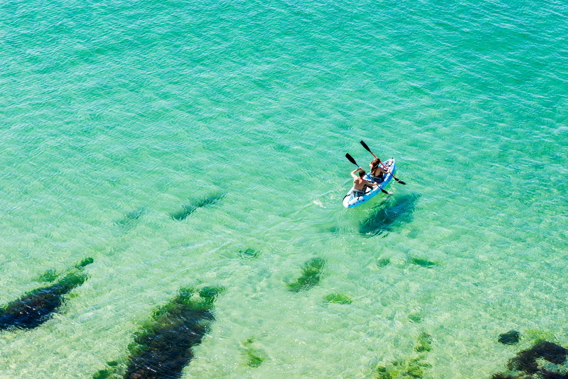 Sea kayakers exploring crystal-clear turquoise waters along the Cornwall coast