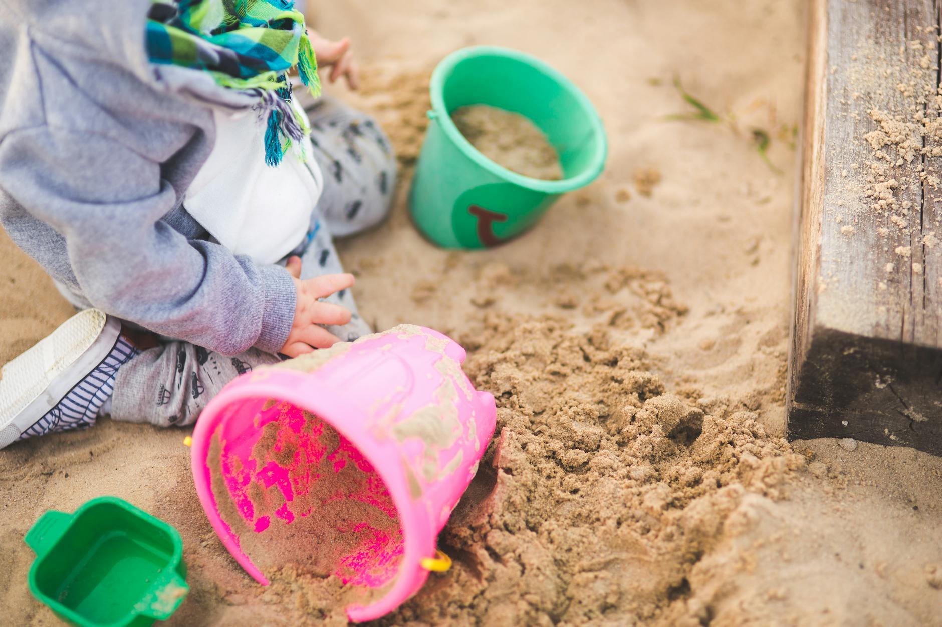 Toddler playing on Cornish beach with bucket and spade