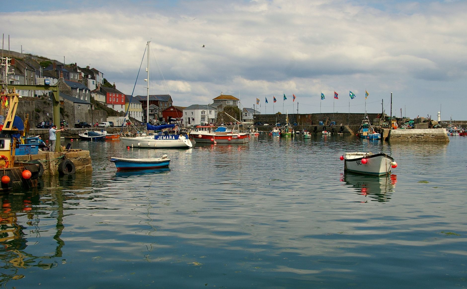 Rain sweeping across a Cornish harbour with fishing boats and grey sea