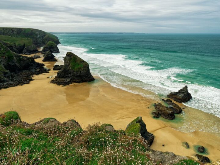 Sea stacks standing on the wide sandy beach at Bedruthan Steps at low tide, seen from the clifftop