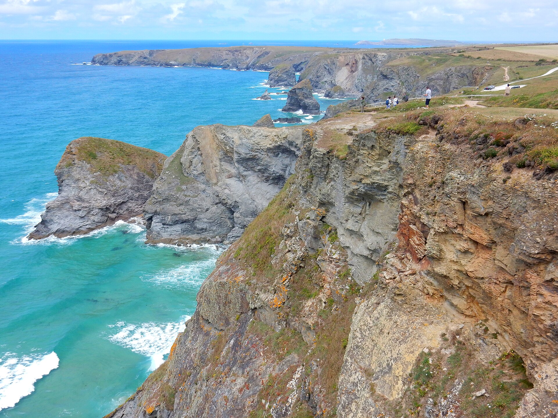 Walkers on the clifftop path above the stacks at Carnewas, Bedruthan Steps, with Trevose Head beyond
