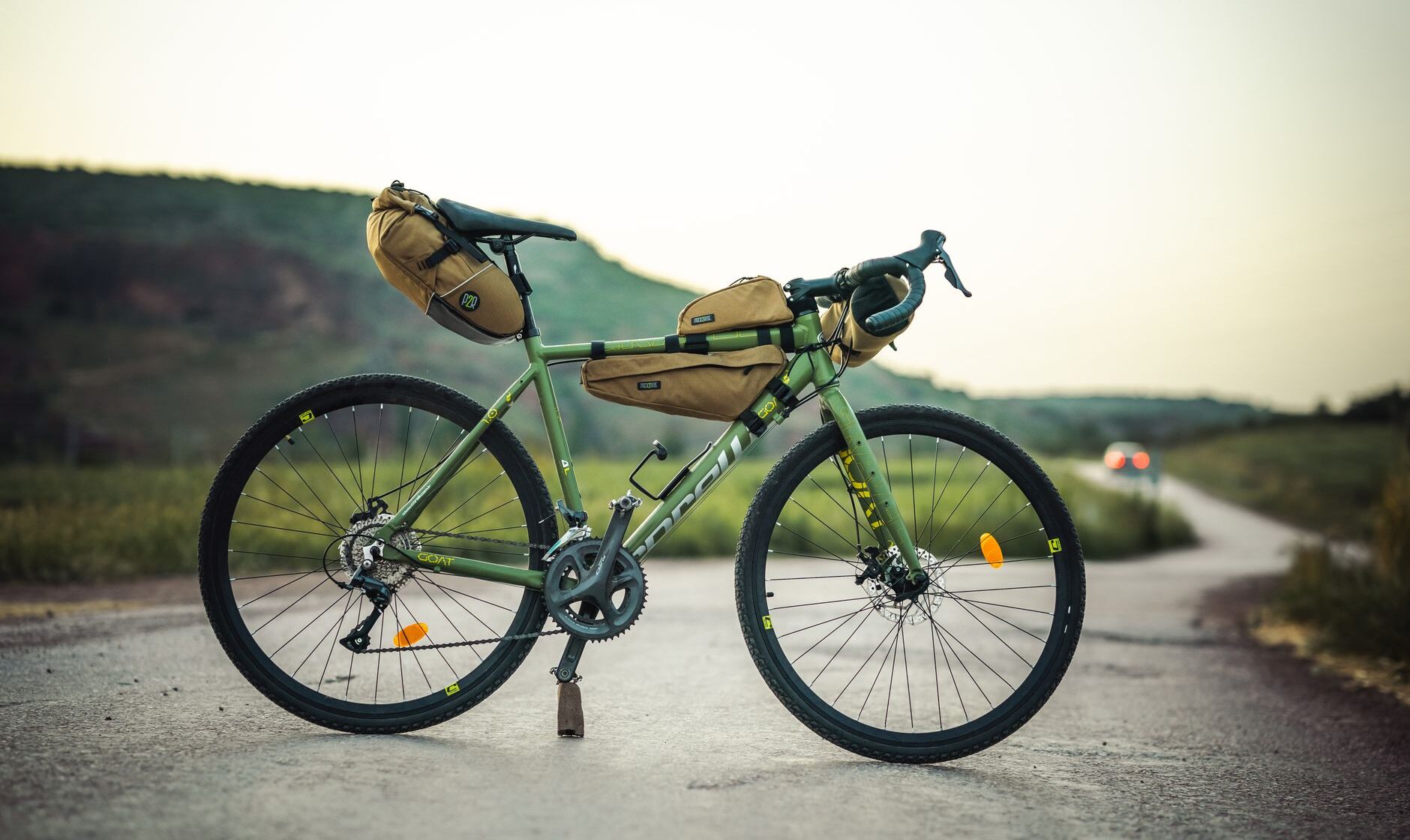 A gravel bike loaded with bikepacking frame, seat and handlebar bags on a rural road