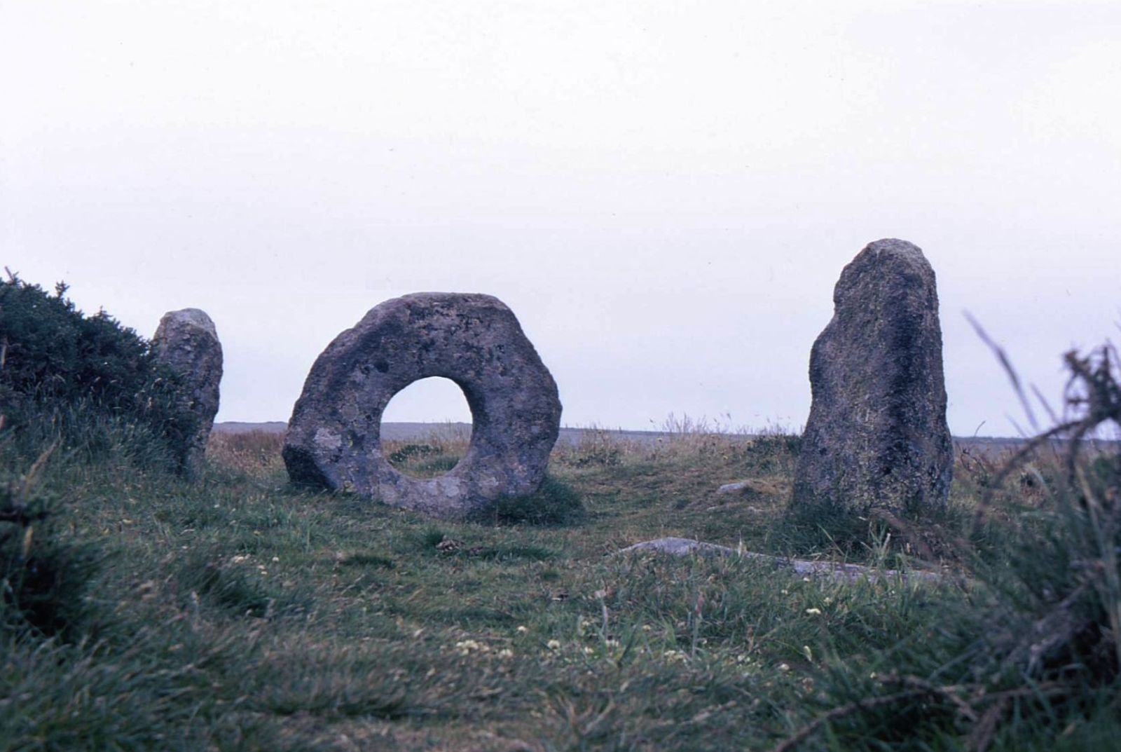 The holed stone of Mên-an-Tol between two standing stones on the Penwith moors