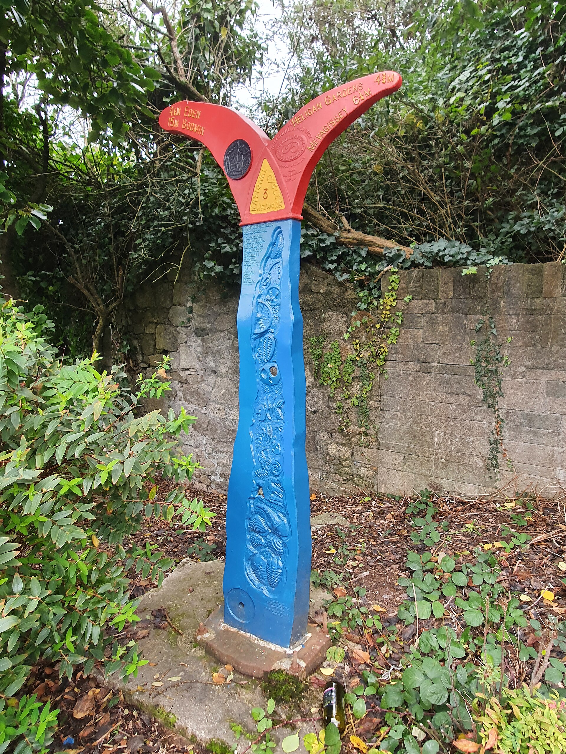 A red and blue National Cycle Network Route 3 milepost pointing to Eden, Bodmin, Heligan and Mevagissey