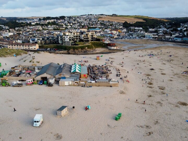 Aerial view of the Watering Hole bar on the sand at Perranporth beach, with the village behind