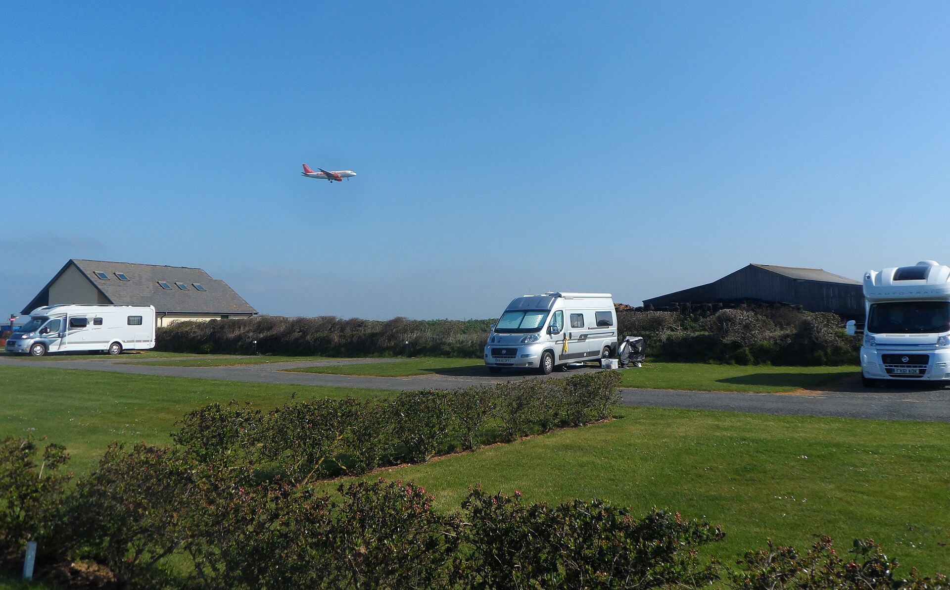 Motorhomes on the campsite at Tregurrian above Watergate Bay, with a plane coming in to land at Newquay airport